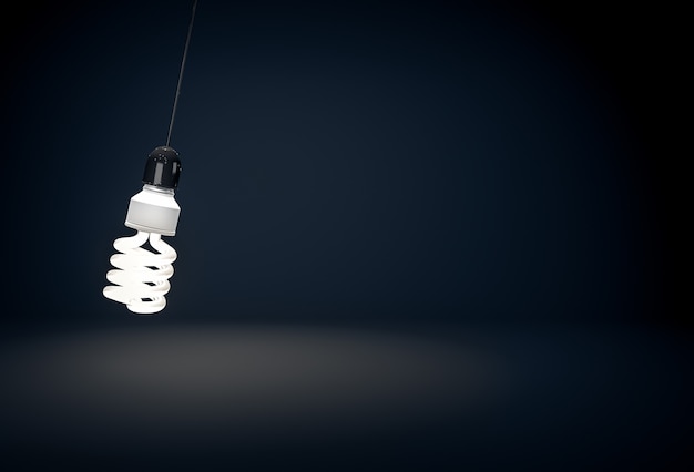 Uma lâmpada de economia de energia ecológica brilhante pendurada em um arame em um quarto escuro