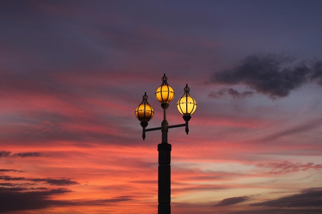 Uma lâmpada de rua à noite com um céu colorido atrás dela.