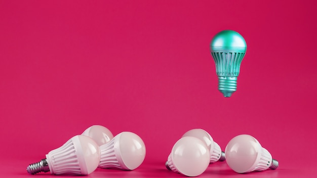 Uma lâmpada especial paira sobre simples lâmpadas brancas padrão em um fundo rosa