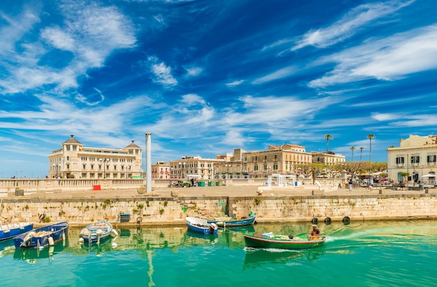 Uma lancha navegando ao longo do canal em Ortygia. Vista da cidade da famosa cidade siciliana, Itália