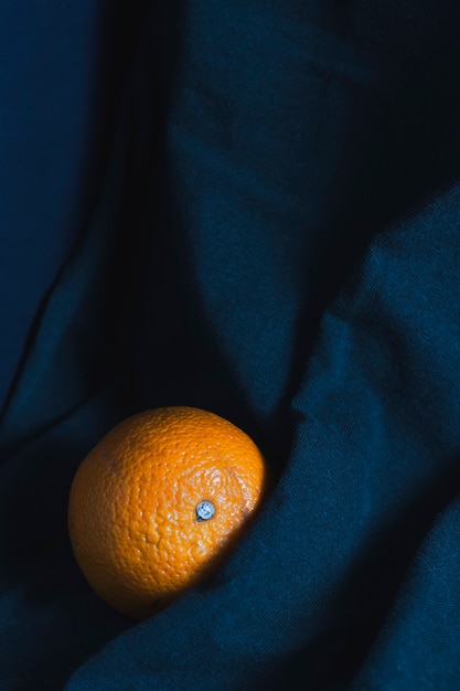 Uma laranja madura nas dobras de um pano azul