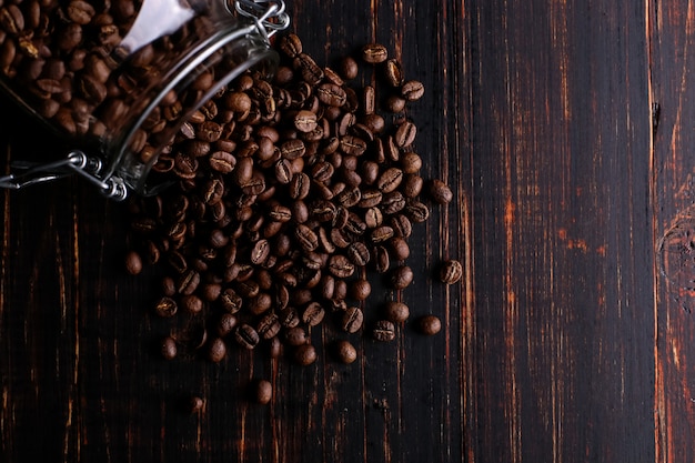 Uma lata de café, grãos espalhados sobre uma mesa de madeira.