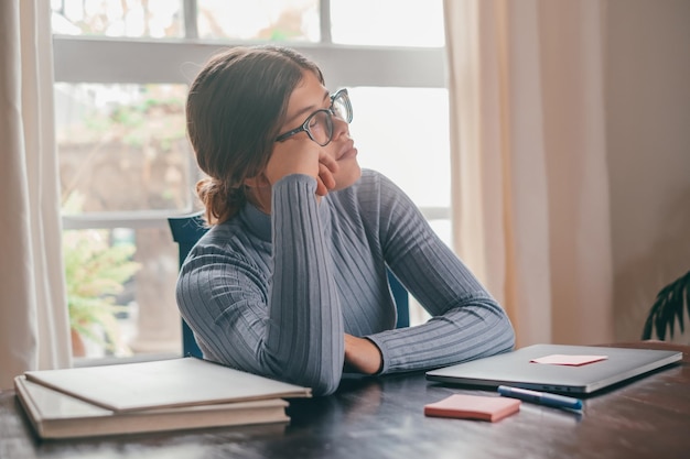 Uma linda adolescente dormindo e descansando na mesa enquanto estuda ou trabalha em casa Millennial fazendo uma pausa depois de fazer a lição de casa usando o laptop