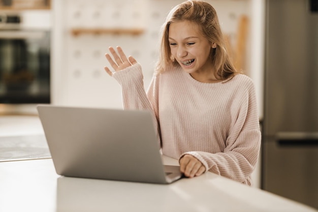 Uma linda adolescente fazendo uma chamada de vídeo em um laptop em sua casa.