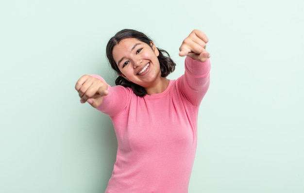 Uma linda adolescente se sentindo feliz e confiante, apontando para a câmera com as duas mãos e rindo, escolhendo você