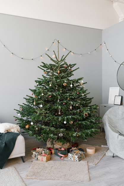 Uma linda árvore de natal com brinquedos e um sofá com almofadas no interior da sala