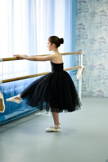 Uma linda bailarina de vestido preto está noiva no stonk Ela está em um estúdio de dança