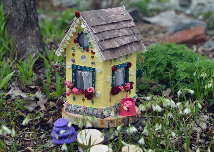 Foto uma linda casa de bonecas de fada com flores de primavera lá fora no jardim.