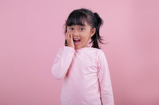 Uma linda criança com expressão chocada usando uma camiseta rosa suave