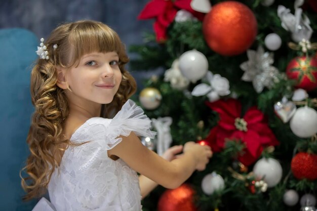 Uma linda criança decora uma árvore de Natal Menina elegante na época do natal