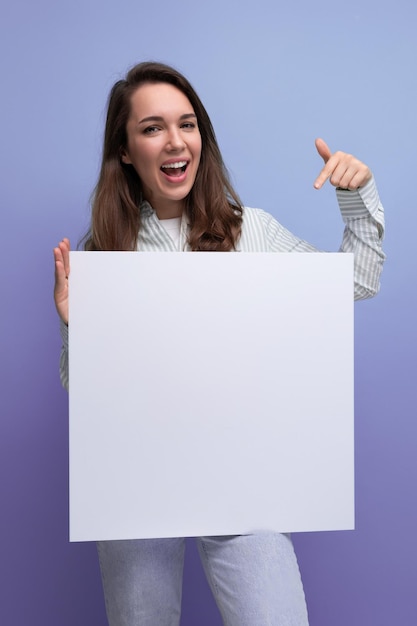 Foto uma linda empresária morena de camisa e jeans mostra informações em um lençol branco