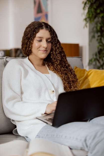 Uma linda garota alegre sorridente olha para a tela do laptop toca os dedos no teclado