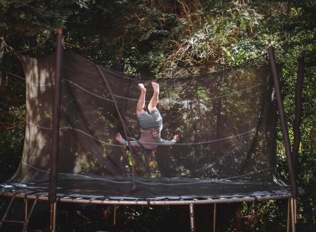 Foto uma linda garota caucasiana em shorts e uma camiseta de manga pula em um trampolim