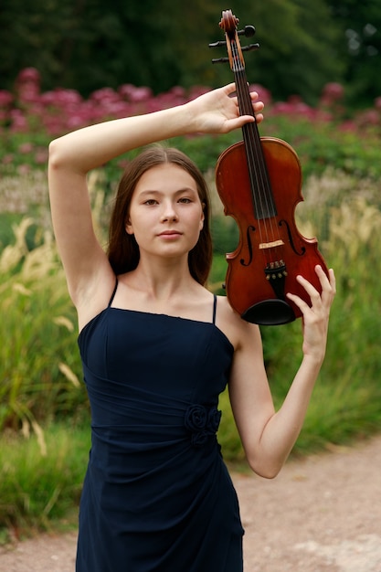 Uma linda garota com longos violinistas fica no parque no verão. Foto de alta qualidade