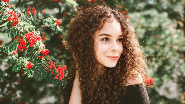 Foto uma linda garota de cabelos cacheados perto de um arbusto