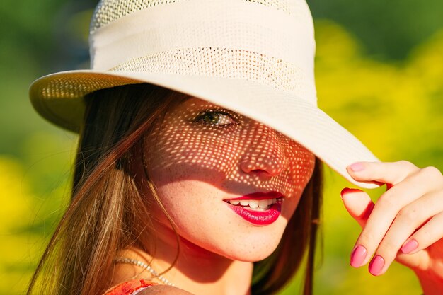 Uma linda garota de chapéu olha para as lentes da câmera e inclina o chapéu