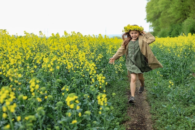 uma linda garota de seis anos atravessa um campo de colza com um buquê de flores