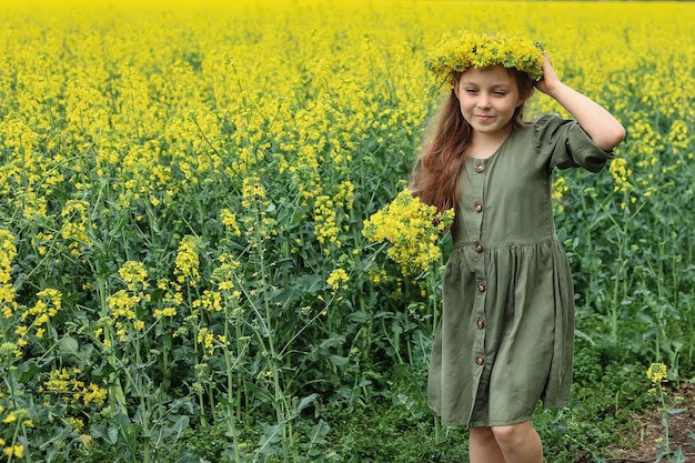 uma linda garota de seis anos caminha por um campo de colza com um buquê de flores