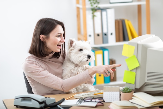 Uma linda garota e um cachorro branco trabalham em um computador retrô