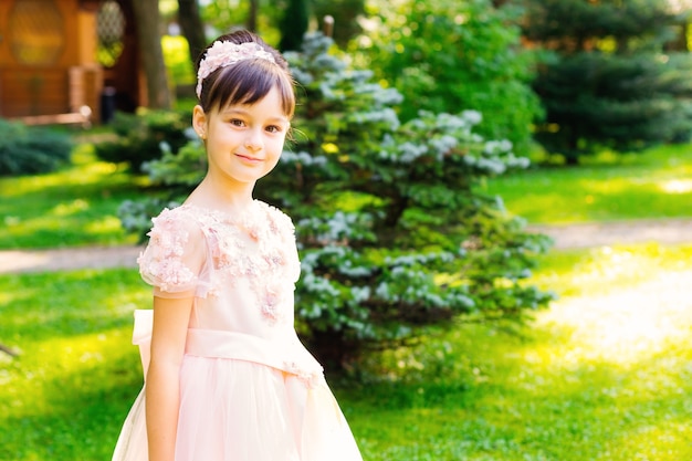 Uma linda garota em um lindo vestido rosa olha para a câmera