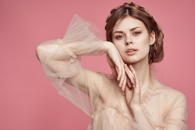 Uma linda garota em um vestido delicado mostra com as mãos um sinal de coração e amor e sorri