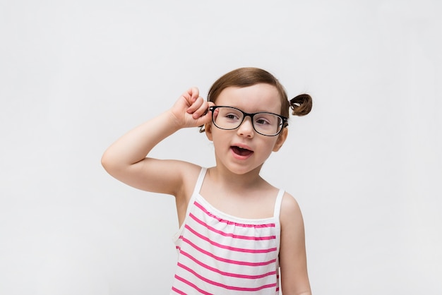 Uma linda garota em um vestido listrado e óculos transparentes sorri. Miopia. Educação