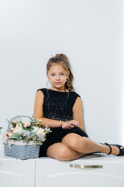 Foto uma linda garota em um vestido preto está sentado e sorrindo com um buquê de flores.