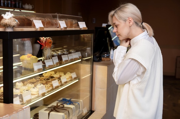 Uma linda garota está de pé na janela em uma confeitaria