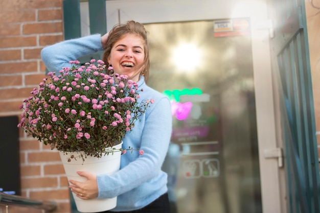 Foto uma linda garota está segurando um grande buquê de flores e sorrindo jovem feliz na cidade
