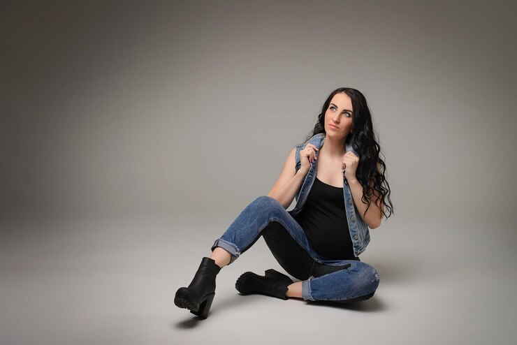 Foto uma linda garota grávida em roupas jeans em um fundo cinza