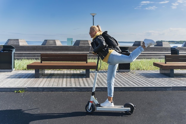 Uma linda garota monta uma scooter elétrica em um passeio em Tallinn em um dia de verão