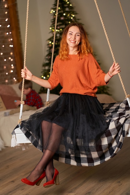 Uma linda garota ruiva está balançando em seu quarto na noite de natal.