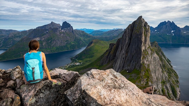 uma linda garota senta-se nas rochas apreciando a vista da famosa montanha segla na noruega, senja