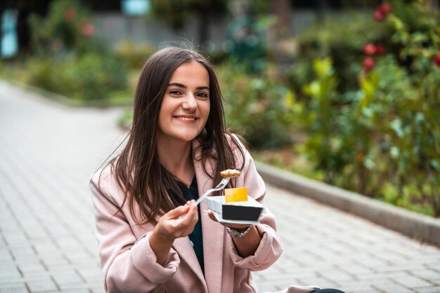 Uma linda garota sorridente come poffertjes frescos enquanto passeia pela cidade Foco seletivo