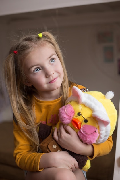 uma linda garota tem nas mãos um patinho popular com bochechas rosadas um pato amarelo com óculos