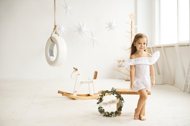 Uma linda garotinha brincando com um barco de balanço no quarto branco