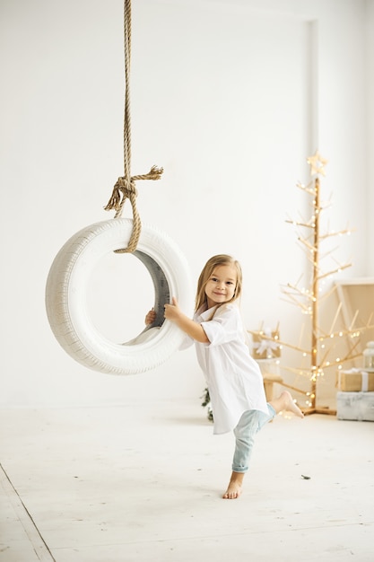 Uma linda garotinha brincando com um barco no quarto branco