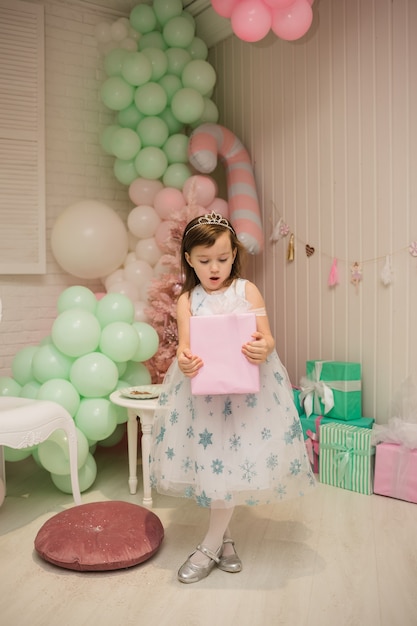 Uma linda garotinha com um vestido fofo e um presente na decoração de ano novo