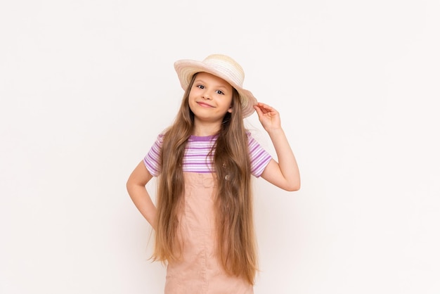 Uma linda garotinha em um vestido de verão e um chapéu de palha está se preparando para umas férias de verão férias de verão para crianças fundo isolado branco