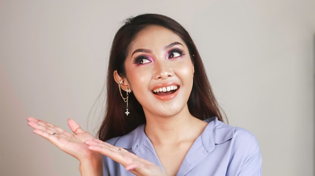 Foto uma linda jovem asiática com maquiagem colorida em um fundo branco olha para o quadro