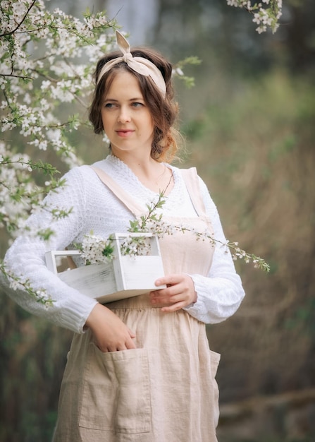 Uma linda jovem de avental aproveita a vida em um jardim florescente de primavera com árvores floridas