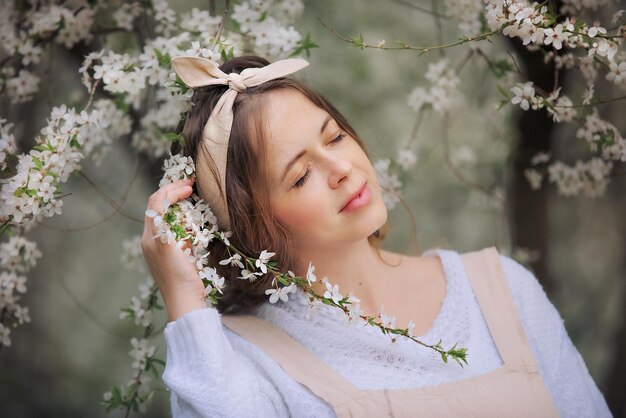 Uma linda jovem de avental aproveita a vida em um jardim florescente de primavera com árvores floridas