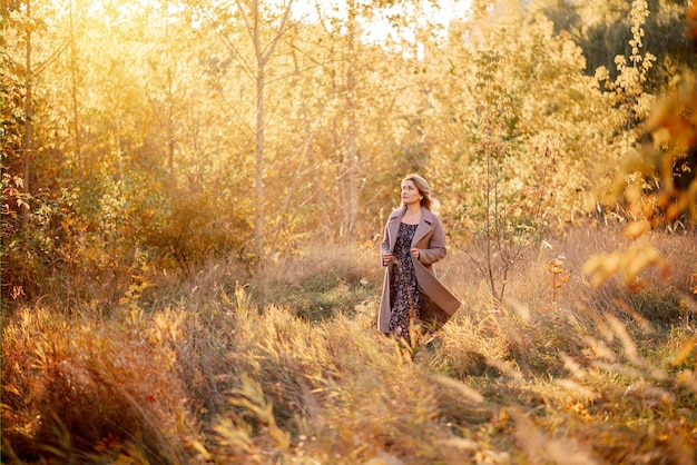 Uma linda jovem de casaco caminha em um parque de outono Golden Autumn Landscape