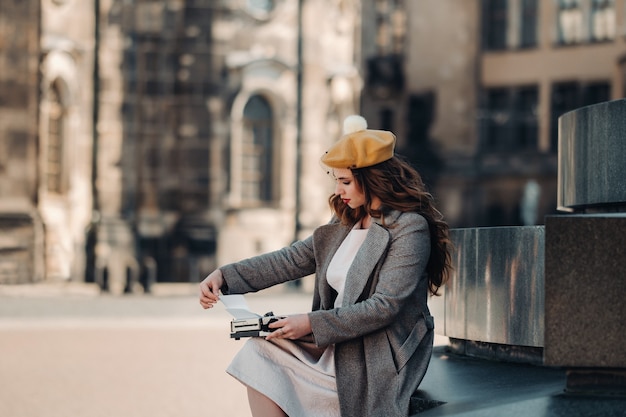 Uma linda jovem elegante está sentada e digitando na cidade velha de Dresden