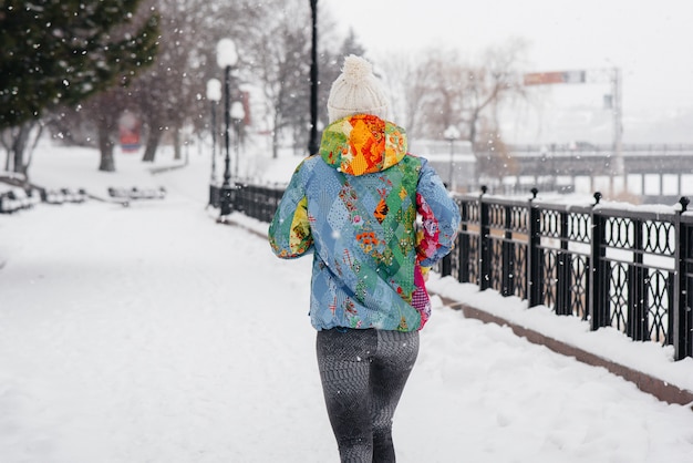 Uma linda jovem está correndo em um dia gelado e com neve. esportes, estilo de vida saudável