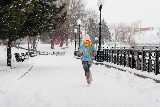 Uma linda jovem está correndo em um dia gelado e com neve. esportes, estilo de vida saudável.