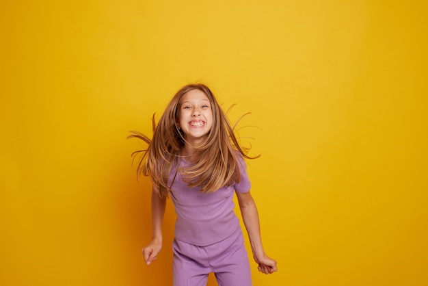 Uma linda jovem está dançando rindo e se divertindo em um fundo amarelo limpo