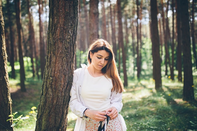 Uma linda jovem hippie caminha na floresta de verão, ri, dança e aproveita a vida e a natureza