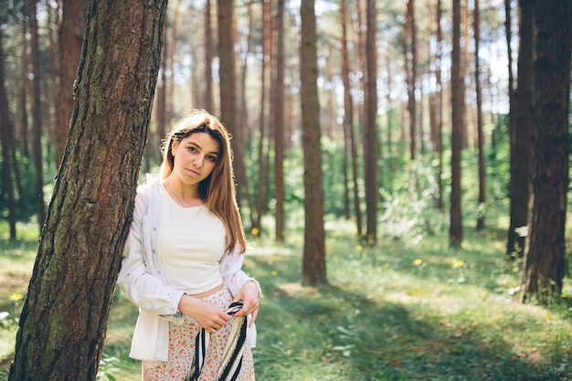 Uma linda jovem hippie caminha na floresta de verão, ri, dança e aproveita a vida e a natureza