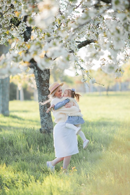 Uma linda jovem mãe com sua filha estão descansando em um piquenique no jardim florido